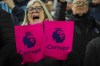 An Everton supporter shows cards reading 'Corrupt' during the English Premier League soccer match between Everton and Manchester United, at Goodison Park Stadium, in Liverpool, England, Sunday , Nov. 26, 2023. (AP Photo/Jon Super)