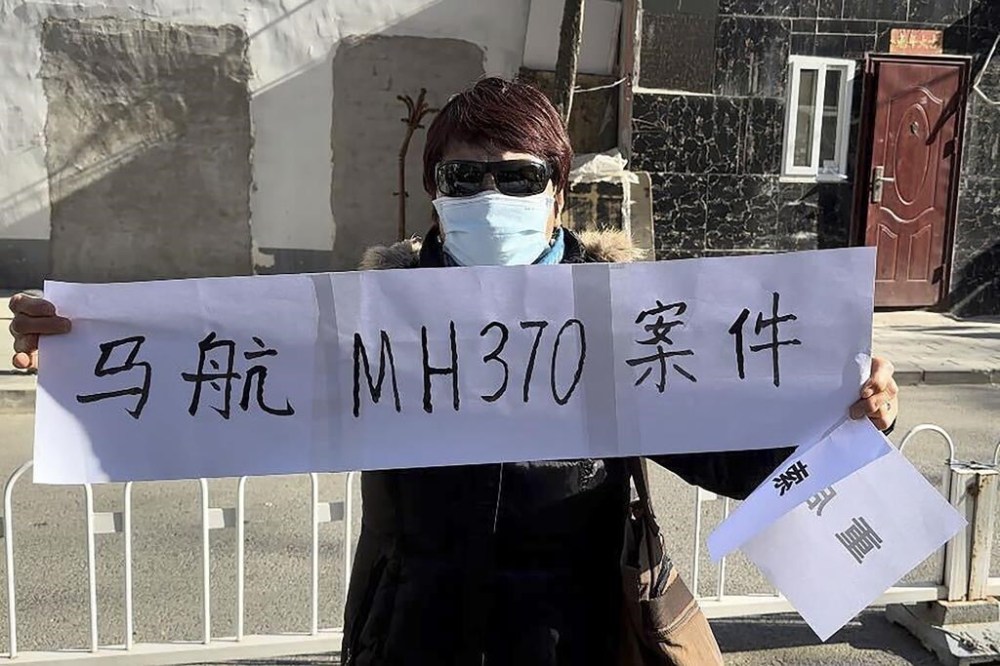 Hu Xiufang, whose son, daughter-in-law and granddaughter were on the missing MH370, hold a banner in Beijing Monday, Nov. 27, 2023. A Beijing court began compensation hearings Monday morning for Chinese relatives of people who died on a Malaysia Airlines plane that disappeared in 2014 on a flight to Beijing, a case that remains shrouded in mystery after almost a decade. The banner reads