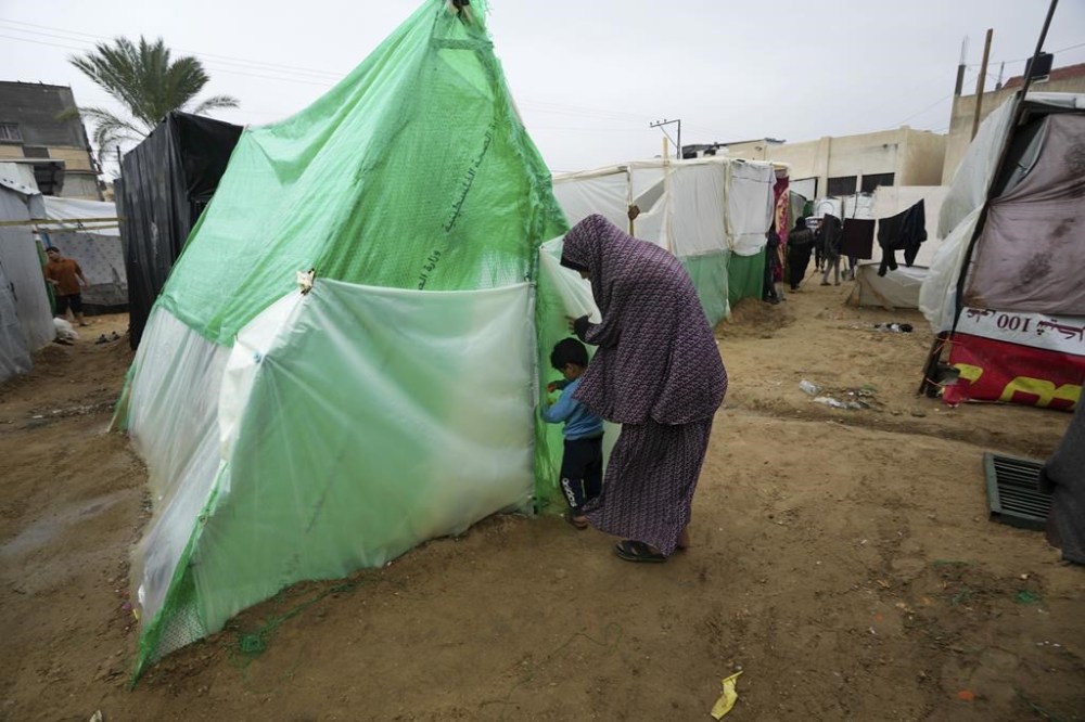 Palestinians displaced by the Israeli bombardment of the Gaza Strip enter a makeshift tent near al Aqsa Hospital in Deir al Balah, Gaza Strip, Monday, Nov. 27, 2023. on the fourth day of the temporary ceasefire between Hamas and Israel. (AP Photo/Adel Hana)