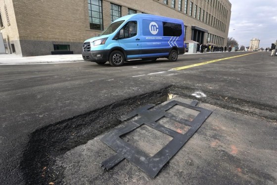 An electric van drives past a visible in-road wireless charging coil to be installed in a street in Detroit. (Paul Sancya / The Associated Press)