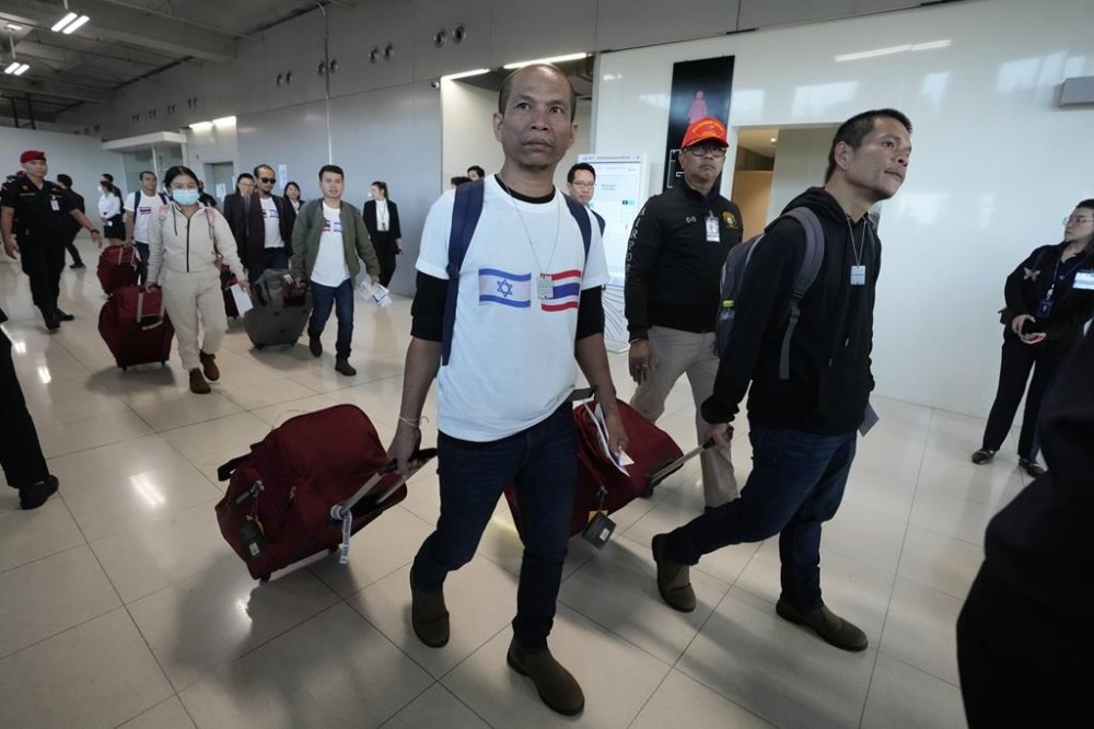 A Thai man wearing a shirt with the Israeli flag, left, and a Thai flag arrives at Suvarnabhumi International Airport in Samut Prakarn Province, Thailand, Thursday, Nov. 30, 2023 after being freed by Hamas. Twenty-three Thai hostages kidnapped by Hamas in its Oct. 7, 2023 attack on southern Israel have been freed so far, and Thailand's foreign ministry says nine remain in captivity in Gaza. There were about 30,000 Thai overseas workers in Israel, mostly in the agricultural sector, but more than 8,000 have returned home since the attack. (AP Photo/Sakchai Lalit)