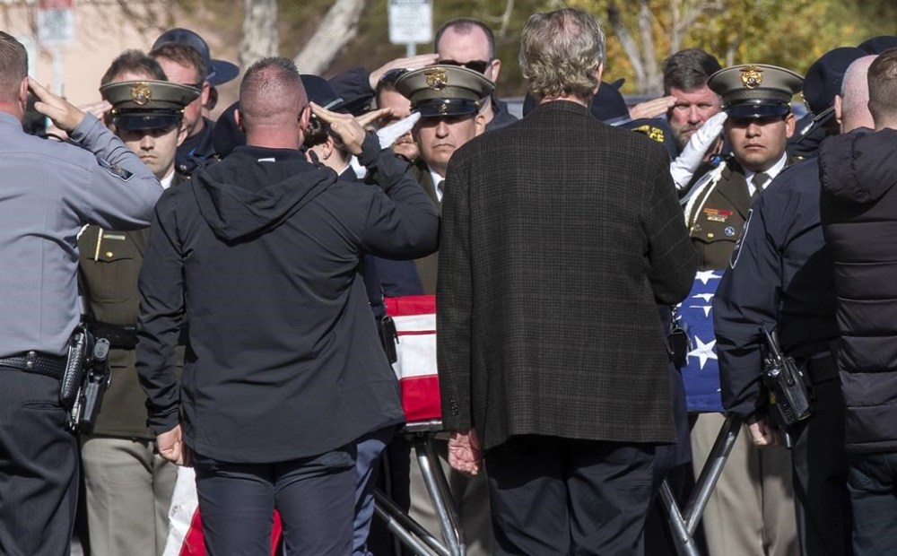 Nevada State Police and other law enforcement officers salute as the body of a state trooper is taken into the Clark County Coroner's Office in Las Vegas, Thursday, Nov. 30, 2023. Two troopers who were assisting a motorist early Thursday morning were hit by a vehicle and killed, according to Nevada State Police. (Steve Marcus/Las Vegas Sun via AP)