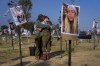 Israeli soldiers embrace next to photos of people killed and taken captive by Hamas militants during their violent rampage through the Nova music festival in southern Israel, which are displayed at the site of the event, to commemorate the October 7, massacre, near kibbutz Re'im, Friday, Dec. 1, 2023. (AP Photo/Ariel Schalit)