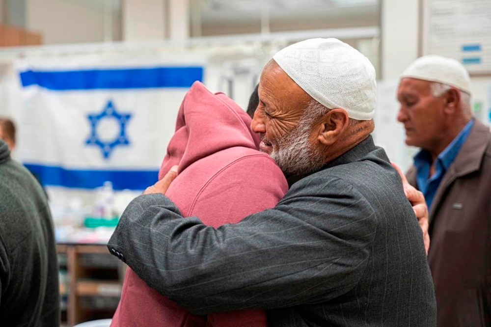 This handout photo provided by GPO on Friday, Dec. 1, 2023, shows Israeli released hostage Bilal Al-Ziyadne, left, reuniting with his family at Soroka Medical Center in Be’er Sheva, Israel. Bilal and his sister Aisha were released the night of Thursday, Nov. 30, 2023. (GPO via AP)