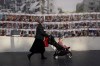 A woman with a baby walks past a wall with photos of the hostages who are believed to remain captive in the Gaza Strip, in Jerusalem, Sunday, Dec. 3, 2023. (AP Photo/Ohad Zwigenberg)