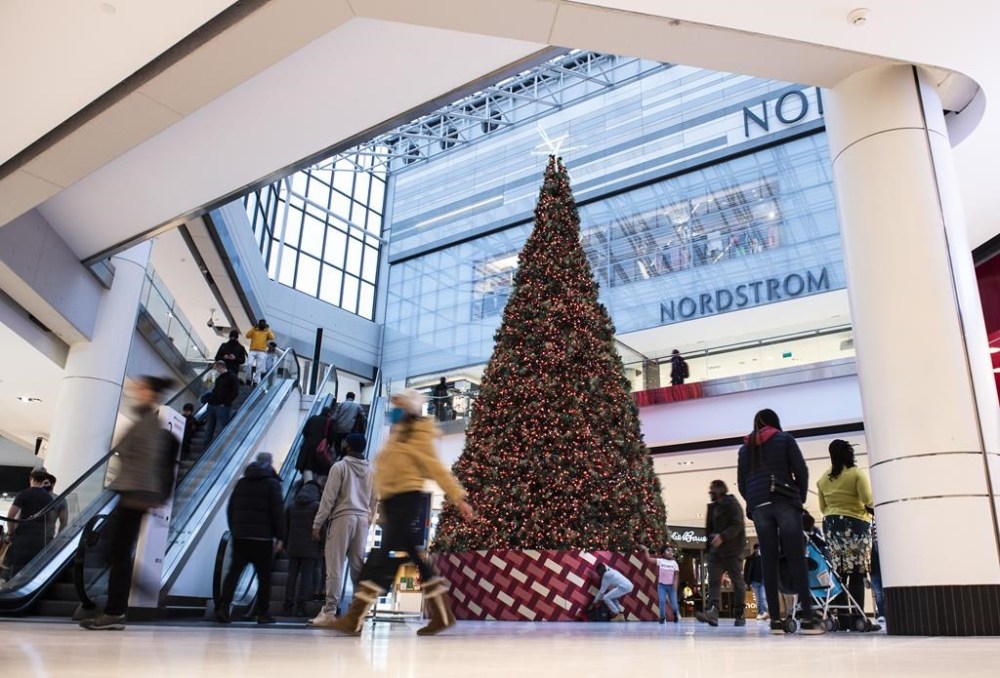 People pass a large Christmas tree as they go shopping on Christmas Eve at a mall in Ottawa on Dec. 24, 2020. Santa is hearing Christmas wishes from children at malls festooned in holiday regalia, stores are teeming with eggnog and gingerbread treats and a barrage of marketing campaigns are promising the perfect gift is just one credit card swipe away.THE CANADIAN PRESS/Justin Tang