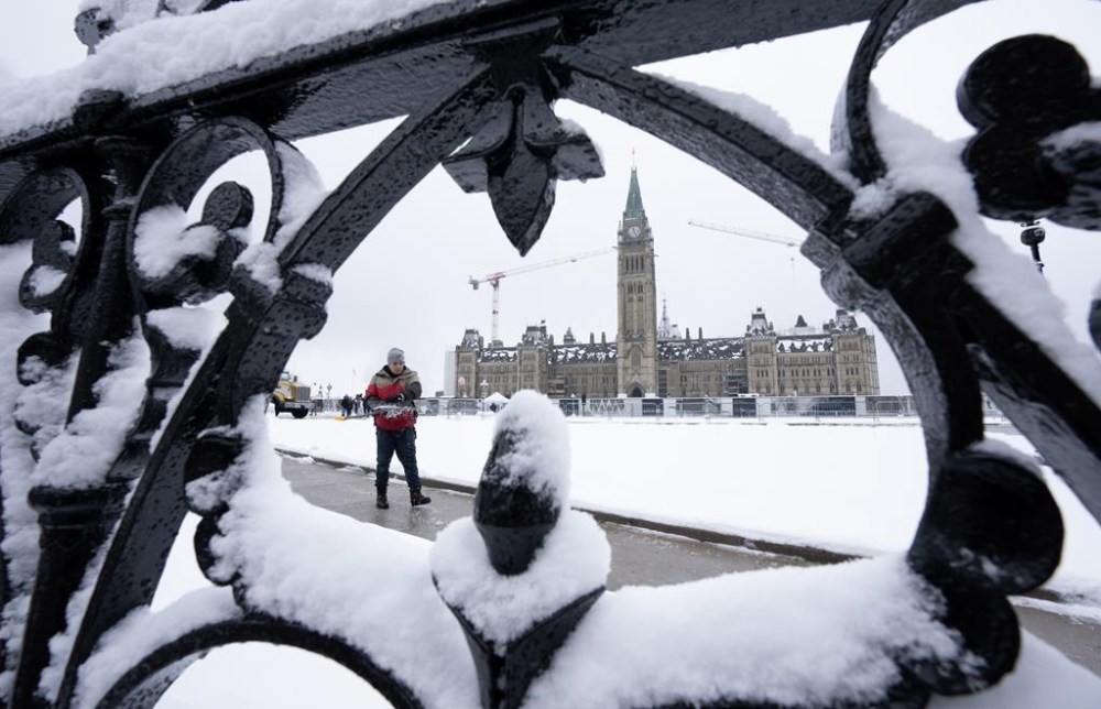 A worker prepares a pathway on Parliament Hill following a snow fall, in Ottawa, Monday, Dec. 4, 2023. The federal government should spend more on health care, a housing strategy, and inflation and cost of living initiatives—and freeze or reduce spending elsewhere, according to a new poll.THE CANADIAN PRESS/Adrian Wyld
