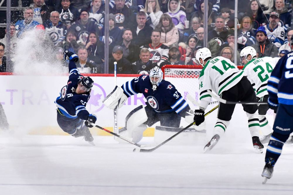 THE CANADIAN PRESS/Fred Greenslade
Winnipeg Jets centre Mark Scheifele, left, reaches to block a shot by Dallas Stars' Jamie Benn in front of goaltender Connor Hellebuyck during the second period in Winnipeg on Tuesday.