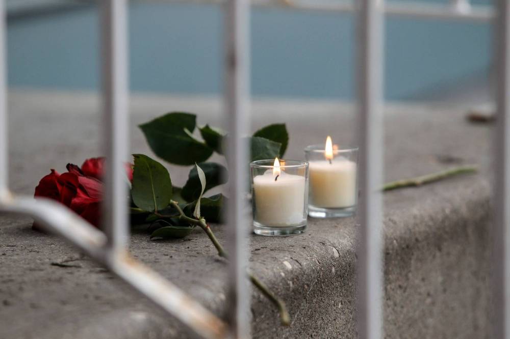 Throughout Sunday afternoon, dozens of community members laid candles, red roses, three teddy bears and a reindeer stuffed animal on the steps of the three-storey home. (John Woods / Winnipeg Free Press)