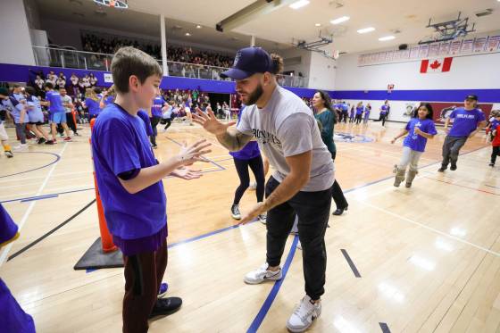 Winnipeg Blue Bomber Brady Oliveira plays a round of Rock, Paper, Scissors with a student in the Rock, Paper, Scissors tournament for charity. (Ruth Bonneville / Winnipeg Free Press)