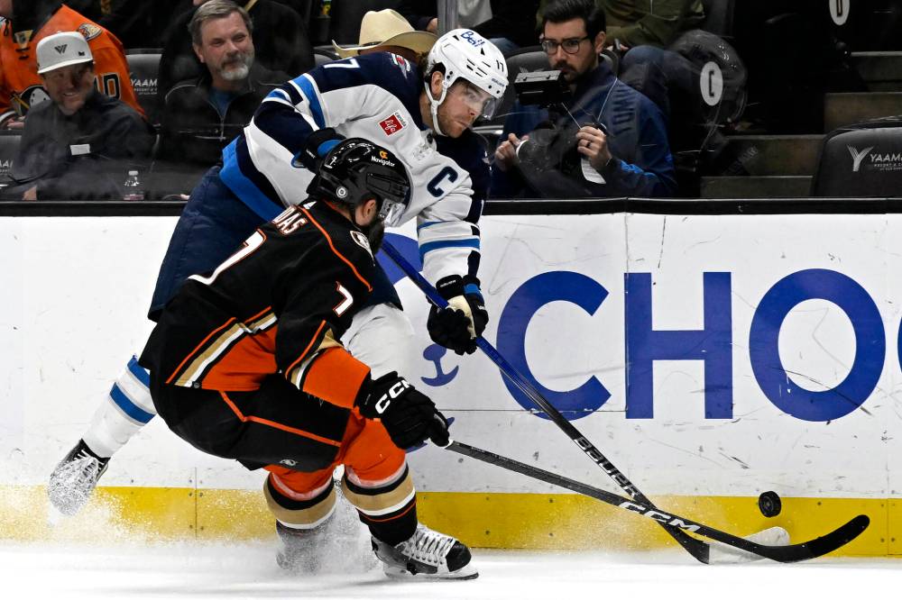 Winnipeg Jets center Adam Lowry (17) gets to the puck before Anaheim Ducks defenseman Radko Gudas (7) during the third period of an NHL hockey game in Anaheim, Calif., Sunday, Dec. 10, 2023. (Alex Gallardo / The Associated Press)