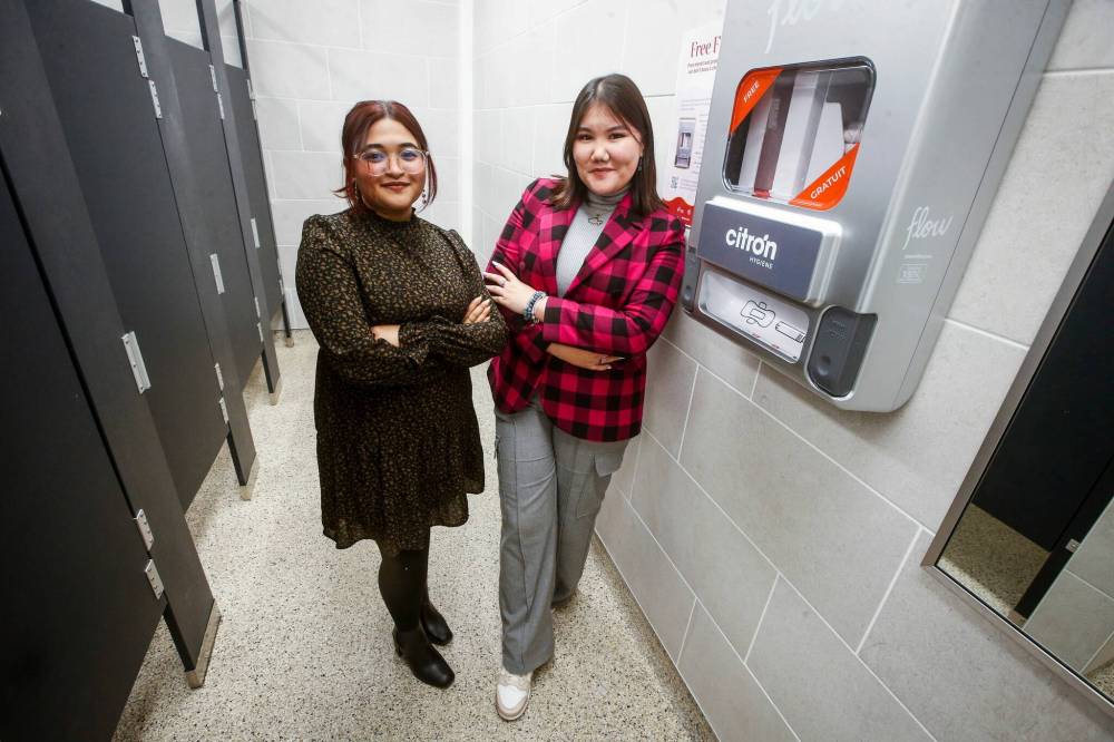JOHN WOODS / WINNIPEG FREE PRESS
University of Winnipeg Student Association (UWSA) president Tomiris Kaliyeva, right, and Christine Quiah, VP of student affairs with one of their menstrual product dispensers in a bathroom on campus Monday.