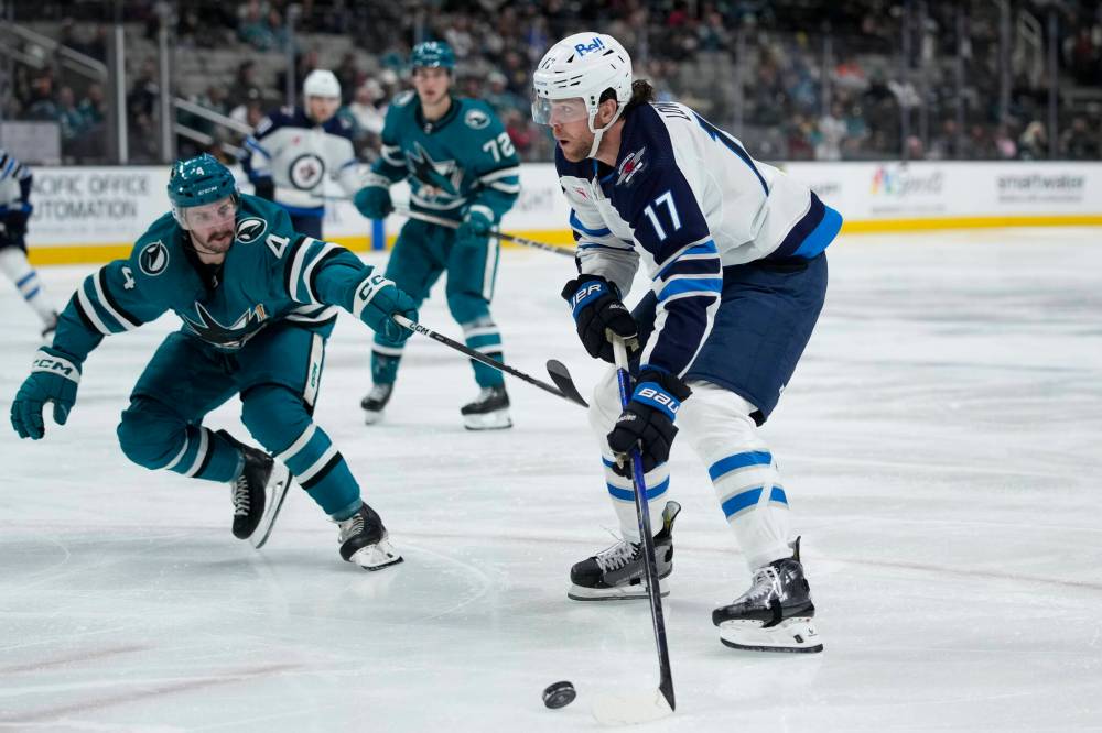 Godofredo A. Vásquez / The Associated Press
Winnipeg Jets centre Adam Lowry moves the puck while defended by San Jose Sharks’ Kyle Burroughs during the second period.