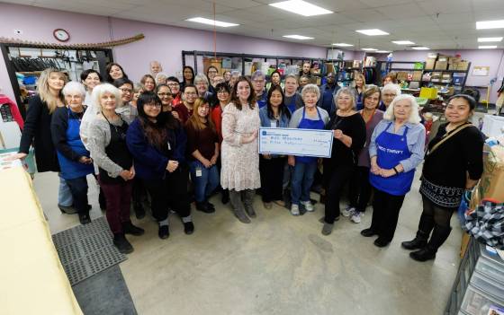 Kildonan MCC Thrift Shop staff and volunteers gather around CEO Lea Pawloski (left) and board chair Karin Brewer holding the cheque marking their record $1 million donation for MCC Manitoba. (Mike Deal / Winnipeg Free Press)