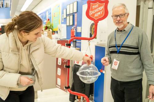 BROOK JONES / WINNIPEG FREE PRESS
                                Maia Mitchell puts money into the Christmas Kettle while John Longhurst rings the bells and hands out candy canes.