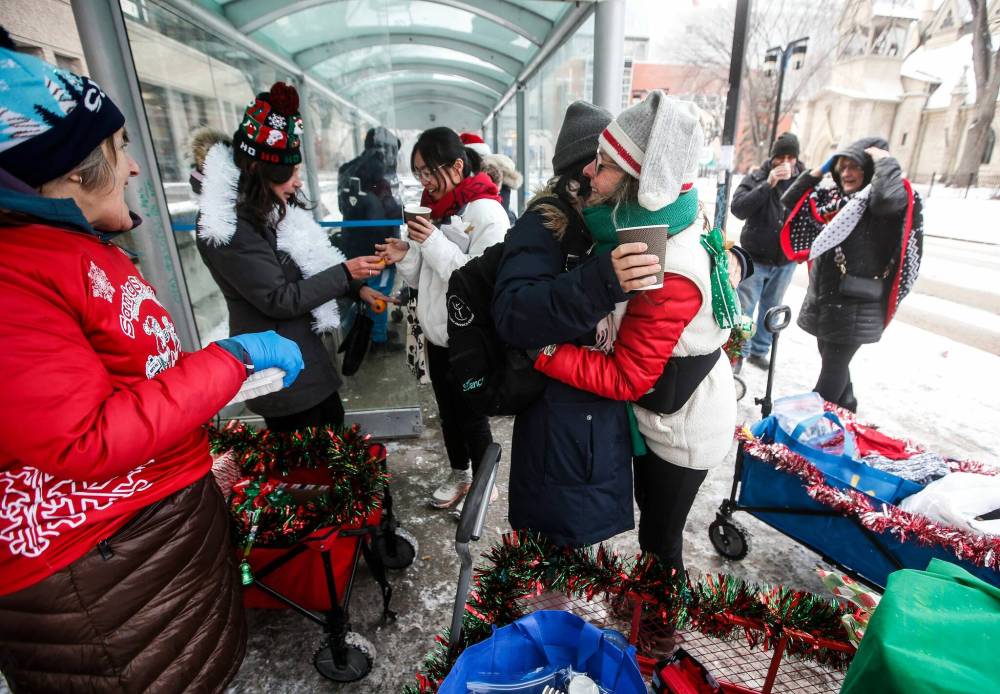 Karen Hammarstrand gets a hug from a bus rider after giving her some hot chocolate as other Urban Wagons volunteers with hand out treats. (John Woods / Winnipeg Free Press)
