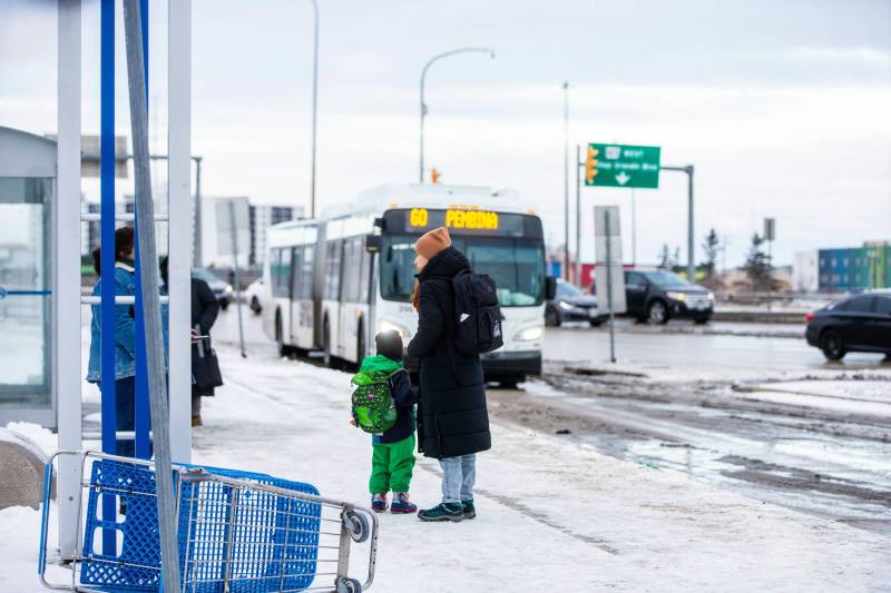 MIKAELA MACKENZIE / WINNIPEG FREE PRESS
Venera Sorkina and her son, Ivan, wait for the second bus on their way back home from Mosaic’s English language class on Monday, Dec. 11, 2023. At this bus stop in the past they have had to go and warm up in a nearby McDonaldճ when multiple buses have been late or cancelled. For Malak story. Winnipeg Free Press 2023