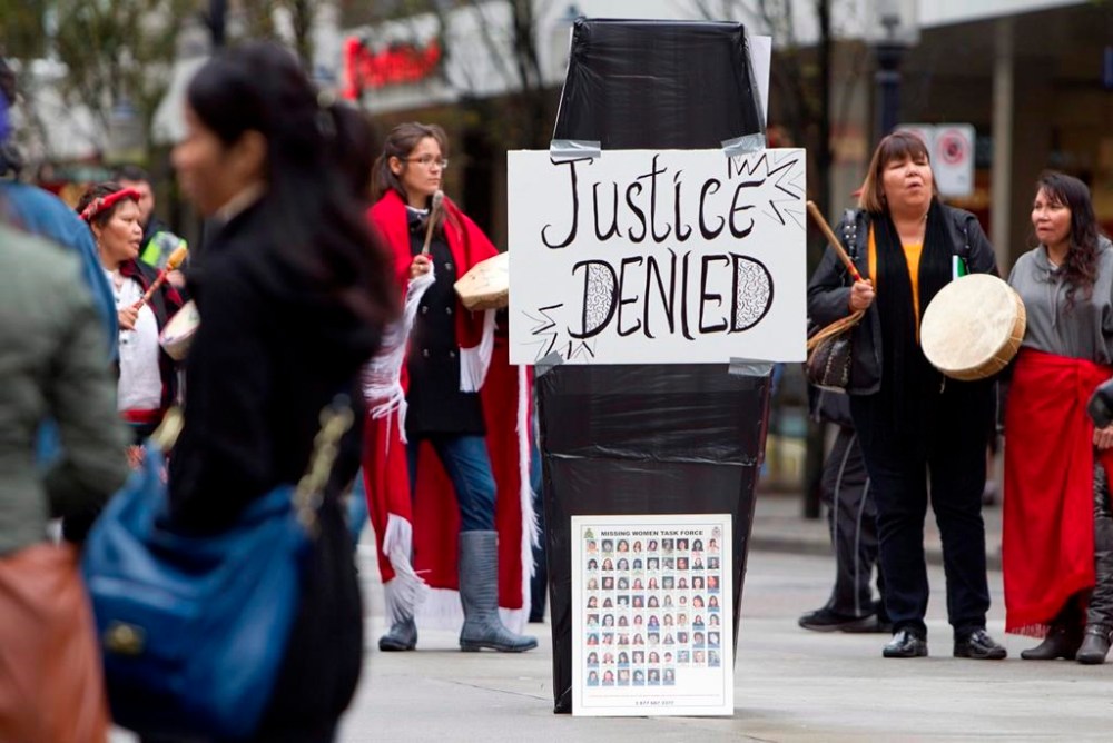 Women sing traditional songs around a mock casket outside the missing women inquiry in downtown Vancouver, Tuesday, Oct. 11, 2011. Advocates and families of victims who were murdered by serial killer Robert Pickton say they are opposed to recent applications filed by the B.C. RCMP to destroy or return thousands of pieces of evidence seized during the investigation. THE CANADIAN PRESS/Jonathan Hayward