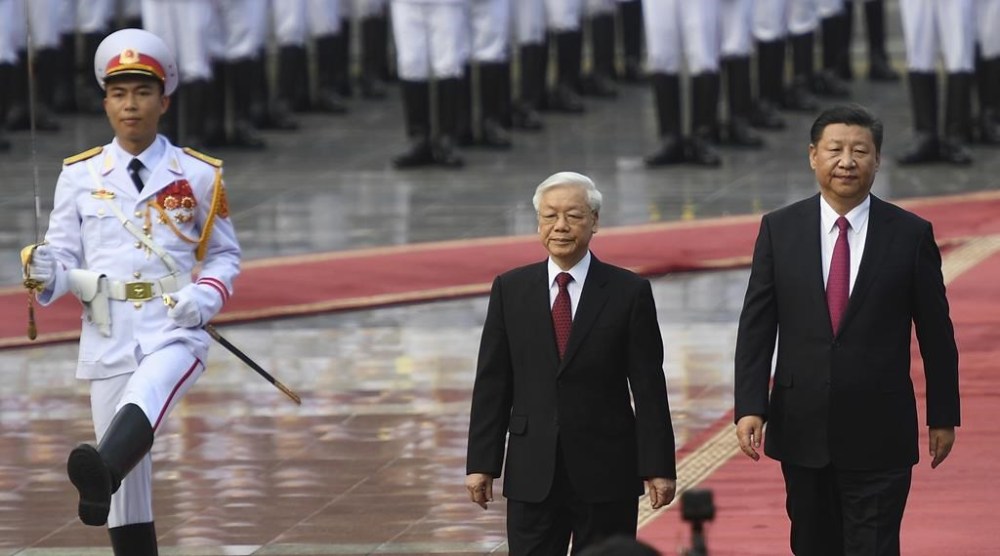 FILE - Chinese President Xi Jinping, right, and Vietnamese Communist Party General Secretary Nguyen Phu Trong, center, review an honor guard during a welcoming ceremony at the presidential palace in Hanoi, Vietnam, Sunday, Nov. 12, 2017. Xi will arrive in Vietnam on Tuesday, Dec. 12, 2023, seeking to further deepen ties with its neighbor that is deepening diplomatic relations with Western-aligned countries. In his first visit since 2017. (Hoang Dinh Nam/Pool Photo via AP, File)
