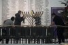 Workers in the Polish parliament clean up a menorah after a far-right lawmaker grabbed a fire extinguisher and put out a candle, disturbing a celebration of the Jewish holiday of Channukah, in Warsaw, Poland, on Tuesday Dec. 12, 2023. (AP Photo/Czarek Sokolowski)