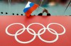 FILE - A Russian flag is held above the Olympic Rings at Adler Arena Skating Center during the Winter Olympics in Sochi, Russia on Feb. 18, 2014. Some Russian athletes will be allowed to compete at the 2024 Paris Olympics, the IOC said Friday, Dec. 8, 2023 in a decision that removed the option of a blanket ban over the invasion of Ukraine. (AP Photo/David J. Phillip, File)