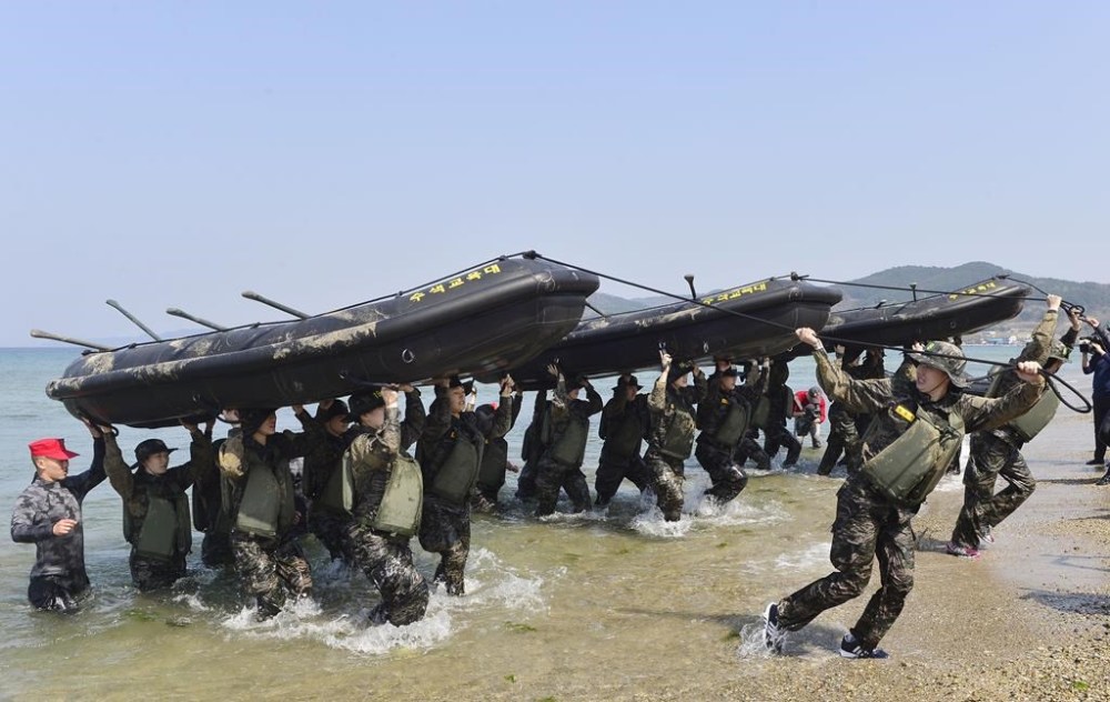 FILE - Members of South Korean women's national handball team perform a team-building exercise with rubber boats during a training at a boot camp for the Marine Corps in Pohang, South Korea, on March 30, 2016. South Korea’s Olympic chief has defended a decision to send hundreds of athletes to a military camp next week as part of preparations for the 2024 Games in Paris, citing a need to instill mental toughness in competitors.(Choe Dong-joon/Newsis via AP, File)