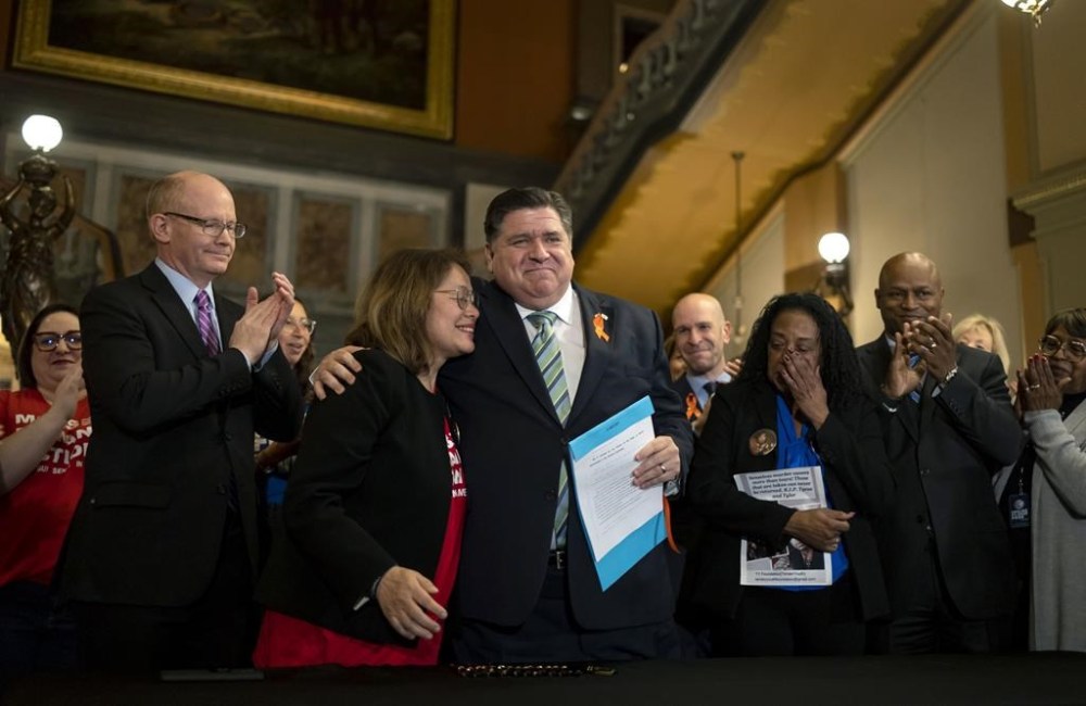 FILE - Illinois Gov. J.B. Pritzker hugs gun control advocate Maria Pike after he signed comprehensive legislation to ban military-style firearms on Jan. 10, 2023, at the Illinois State Capitol in Springfield, Ill. The Supreme Court on Thursday, Dec. 14, declined to put on hold a new Illinois law that would ban high-power semiautomatic weapons like the one used in the mass killing of seven people at a 2022 parade in a Chicago suburb. (Brian Cassella/Chicago Tribune via AP, File)