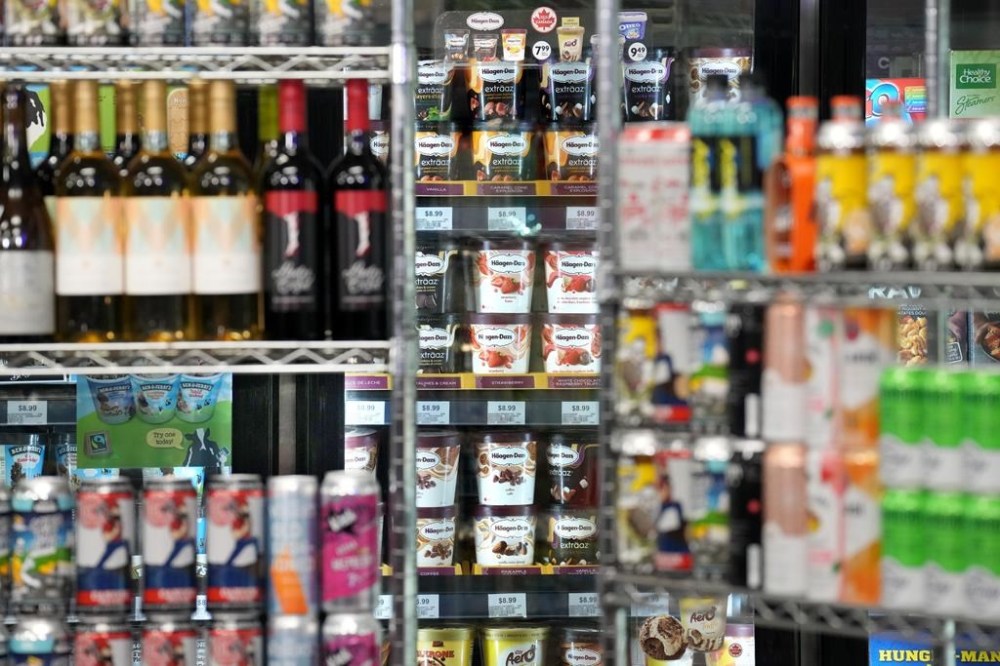 Beer cans are stacked as props in front a display of ice cream, at a press availability attended by Ontario Premier Doug Ford at a convenience store in Toronto, Thursday, Dec. 14, 2023. The Ontario Government announced that in 2026 they will allow beer, wine, cider, coolers and pre-mixed drinks to be sold at convenience stores, grocery stores and