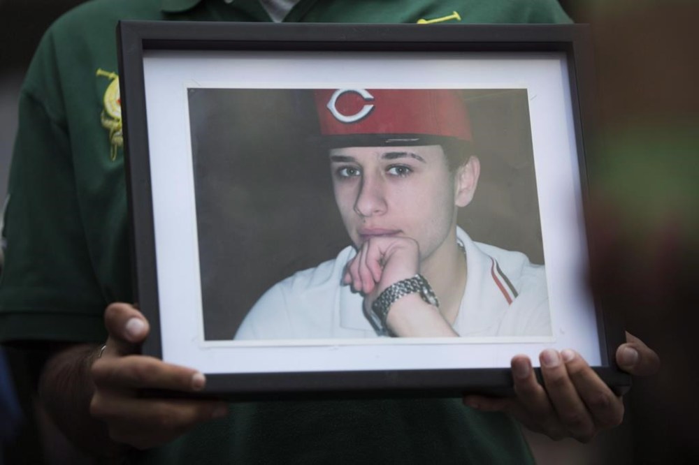A coroner's inquest for Sammy Yatim, a Toronto teen who was shot by a police officer on an empty streetcar in in 2013, is now set to begin next month. A photo of Yatim is held by one of the teen's friends at a Toronto courthouse after the sentencing of Const. James Forcillo in Toronto on Thursday, July 28, 2016. THE CANADIAN PRESS/Michelle Siu