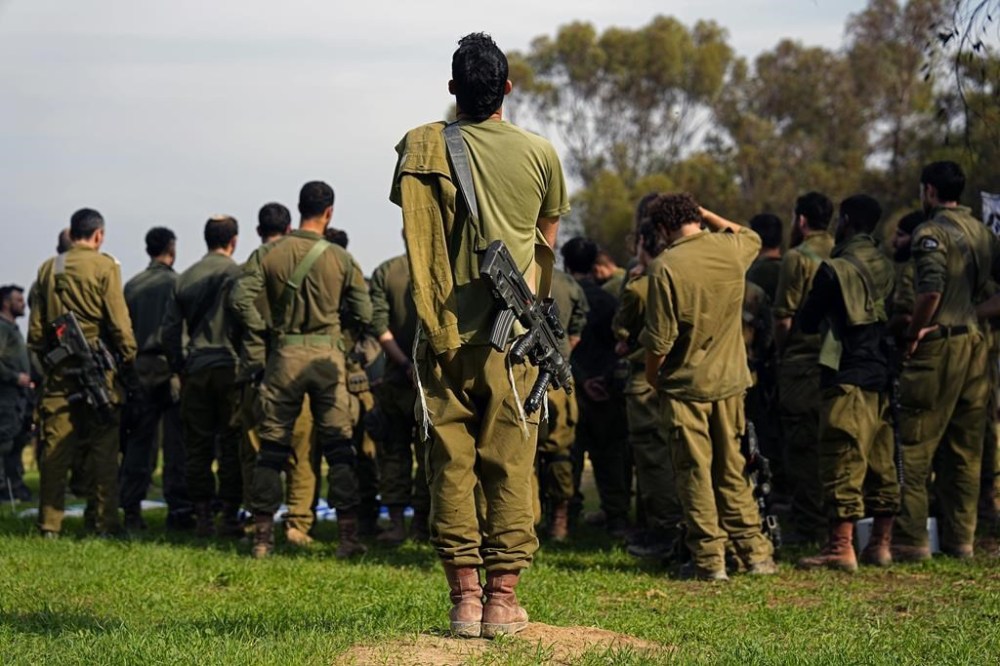 Israeli soldiers gather as they are briefed after coming back from the Gaza Strip at a staging area in southern Israel, Sunday, Dec. 17, 2023. (AP Photo/Ariel Schalit)