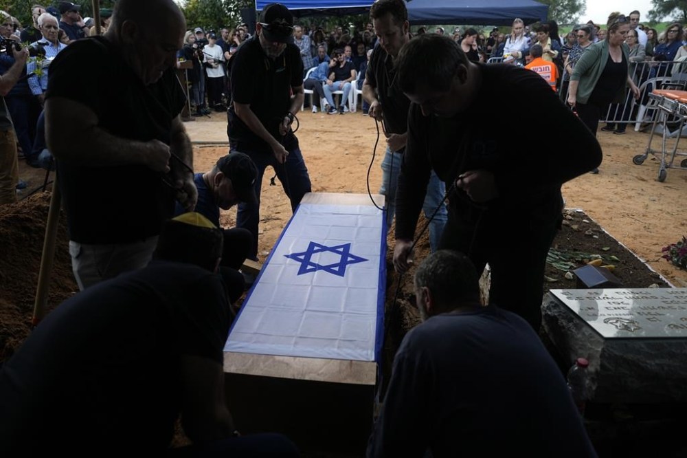 The coffin containing the remains of Alon Shamriz, 26, is lowered to his grave during his funeral in the cemetery of Kibbutz Shefayim, southern Israel, Sunday Dec. 17, 2023. Shamriz was one of three hostages mistakenly shot to death by Israeli troops Friday in a battle-torn neighborhood of Gaza City.(AP Photo/Ohad Zwigenberg)