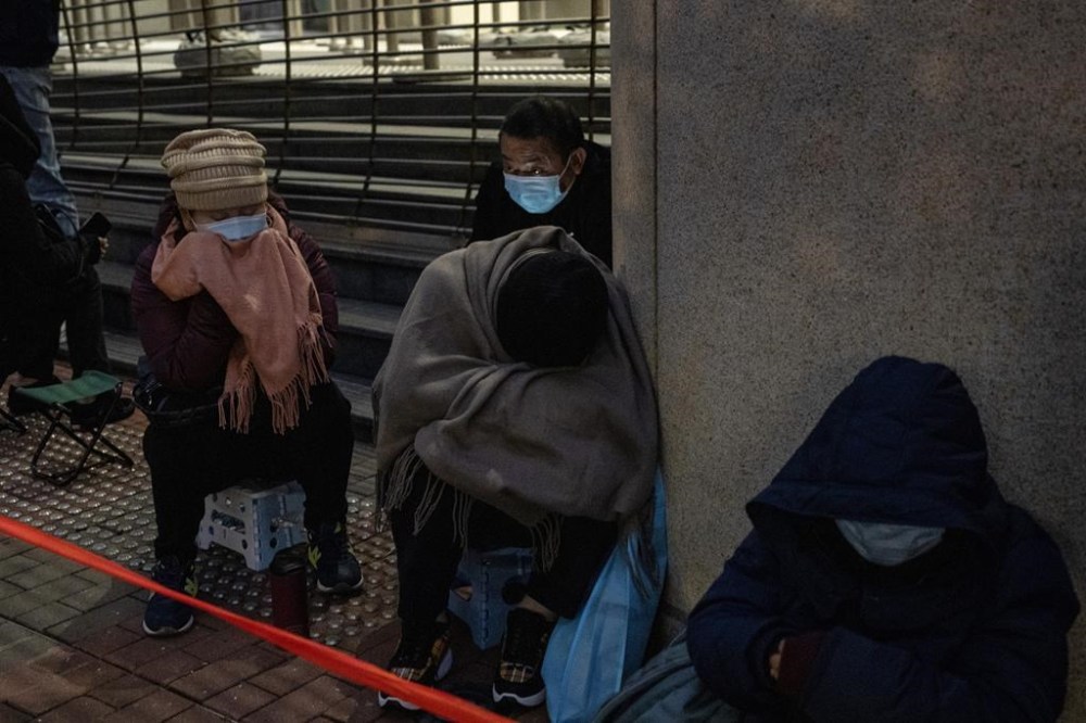 People wait behind a police line set up outside West Kowloon Magistrates' Courts, where Jimmy Lai's trial is scheduled to open, in Hong Kong, Monday, Dec. 18, 2023. (AP Photo/Vernon Yuen)