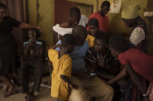 Papa Dieye, 19 ans, au centre à droite, parle à son père, Badara Dieye, alors qu'ils regardent des photos de son sauvetage sur un téléphone portable, entourés d'autres membres de la famille à Diogo, au Sénégal, le lundi 28 août 2023. (AP Photo/Felipe Dana)