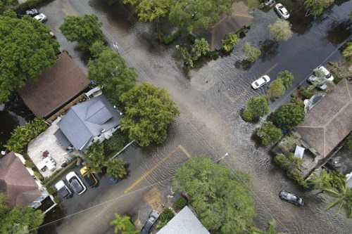 FILE - A pair of waterlogged cars sit abandoned in the road as floodwaters recede in the Sailboat Bend neighborhood of Fort Lauderdale, Fla., April 13, 2023. Flood risk and climate change are pushing millions of people to move from their homes, according to a new study by the risk analysis firm First Street Foundation. (AP Photo/Rebecca Blackwell, File)