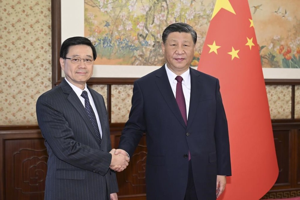In this photo released by Xinhua News Agency, Chinese President Xi Jinping, right, shakes hands with visiting Hong Kong's Chief Executive John Lee prior the meeting in Beijing, Monday, Dec. 18, 2023. Hong Kong's leader John Lee is in Beijing for an annual duty visit and met with Chinese leaders, as the landmark national security trial for prominent activist publisher Jimmy Lai started in Hong Kong on Monday. Lee criticized foreign governments for trying to exert influence on a national security case on trial in Hong Kong. (Li Xueren/Xinhua via AP)