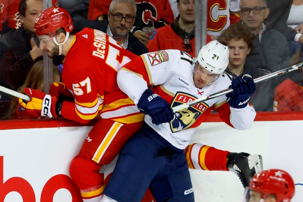 Calgary Flames defenceman Nick DeSimone, right, is hit by Florida Panthers centre Nick Cousins during first period NHL hockey action in Calgary, Alta., Monday, Dec. 18, 2023. THE CANADIAN PRESS/Larry MacDougal
