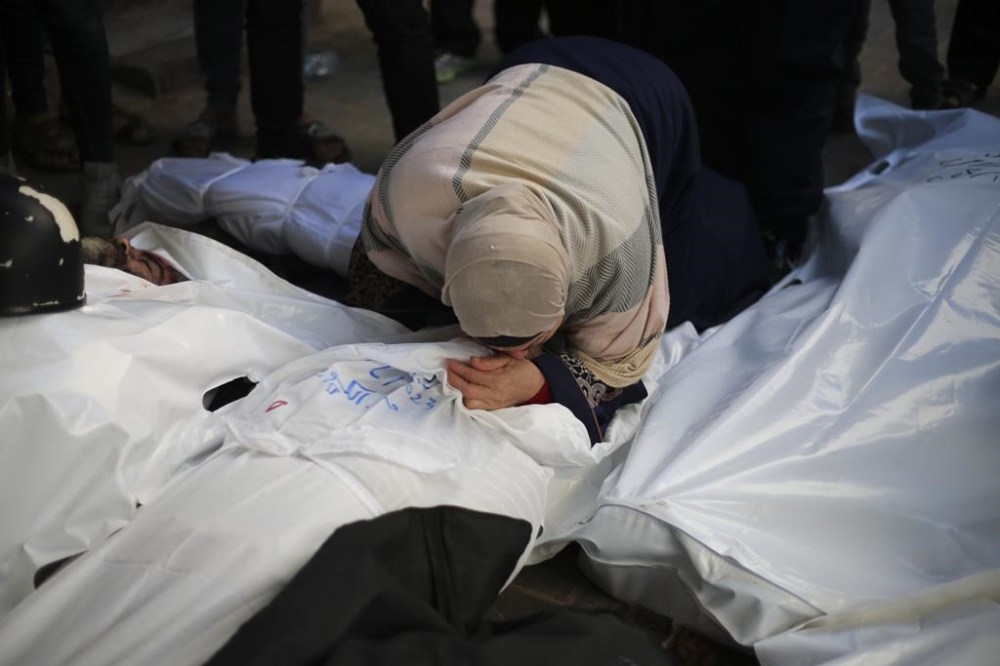 Palestinians mourn relatives killed in the Israeli bombardment of the Gaza Strip outside a morgue in Rafah, Tuesday, Dec. 19, 2023. (AP Photo/Hatem Ali)