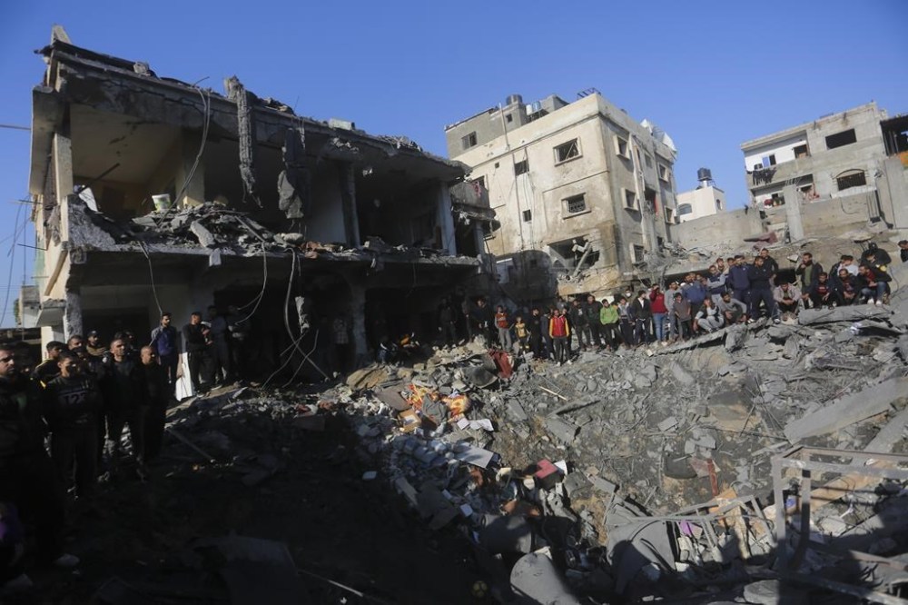 Palestinians watch the destruction after the Israeli bombardment of the Gaza Strip outside a morgue in Rafah, Tuesday, Dec. 19, 2023. (AP Photo/Hatem Ali)