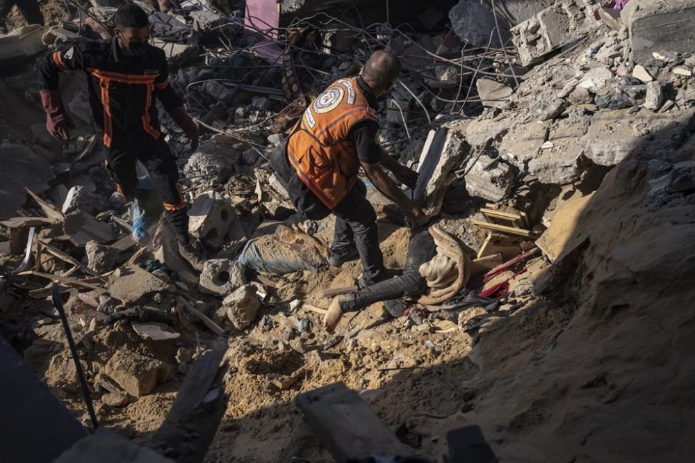 Palestinians pull a body out of the rubble of a residential building destroyed in an Israeli airstrike, in Rafah, southern Gaza Strip, Tuesday, Dec. 19, 2023. (AP Photo/Fatima Shbair)