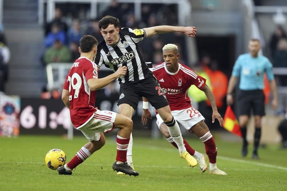 Newcastle United's Tino Livramento, center, looks to get past Nottingham Forest's Gonzalo Montiel, left, during the English Premier League soccer match between Newcastle United and Nottingham Forest at St. James' Park, Newcastle upon Tyne, England, Tuesday, Dec. 26, 2023. (Owen Humphreys/PA via AP)