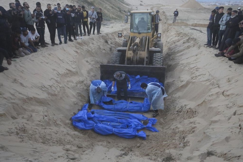 Bulldozer unloads the bodies of Palestinians killed in the north of the Gaza Strip and turned over by the Israeli military during a mass funeral in Rafah, Tuesday, Dec. 26, 2023. (AP Photo/Hatem Ali)