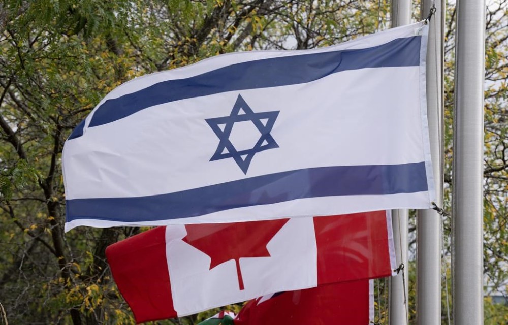 The flags of Canada and Israel fly at half mast at a community building on Wednesday, October 11, 2023 in Ottawa. Friends, family and government officials have confirmed that at least seven Canadians were killed when Hamas militants conducted a series of attacks in Israel on Oct. 7. THE CANADIAN PRESS/Adrian Wyld