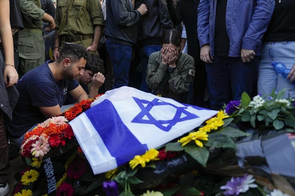 Mourners gather in grief around the grave of Israeli soldier Captain Harel Ittah during his funeral in Netanya, Israel, Sunday, Dec. 31, 2023. Ittah, 22, died of his wounds after he was injured while the army is battling Palestinian militants across Gaza in the war ignited by Hamas' Oct. 7 attack into Israel. (AP Photo/Ariel Schalit)