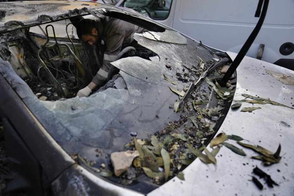 A Hezbollah Civil defense worker searches for body remains inside a burned car, near an apartment building where an apparent Israeli strike Tuesday killed top Hamas political leader Saleh Arouri, in the southern suburb of Beirut that is a Hezbollah stronghold, Lebanon, Wednesday, Jan. 3, 2024. The apparent Israeli strike that killed Hamas' No. 2 political leader, marking a potentially significant escalation of Israel's war against the militant group and heightening the risk of a wider Middle East conflict. (AP Photo/Hussein Malla)