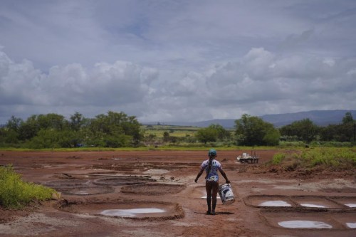 Pi'ilani Taniguchi Butler carries a bucket of wet clay to her family's salt beds on Wednesday, July 12, 2023, in Hanapepe, Hawaii. The salt beds or 