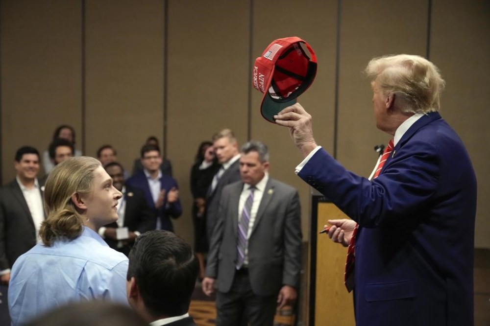 Former President Donald Trump hols up a hat he signed after speaking at a rally at Des Moines Area Community College in Newton, Iowa, Saturday, Jan. 6, 2024. (AP Photo/Andrew Harnik)
