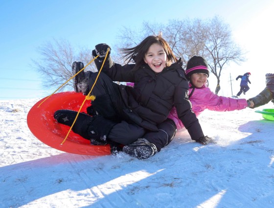 Sisters Olivia (left) and Amelia Ross-Choken scream with laughter as they toboggan down the hill at Westview Park Wednesday. Dad, Joseph, watched from nearby, smiling as they whizzed down the slopes. (Ruth Bonneville / Winnipeg Free Press)