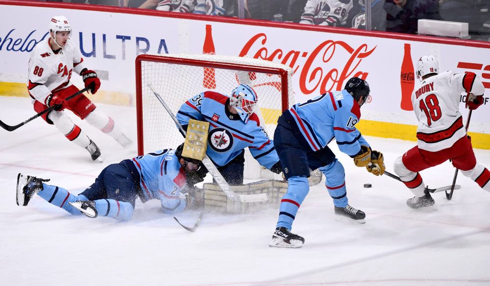 Fred Greenslade / THE CANADIAN PRESS
Winnipeg Jets goaltender Laurent Brossoit keeps an eye on Carolina Hurricanes' Jack Drury as Dylan Demelo slides into him during the first period in Winnipeg on Monday.