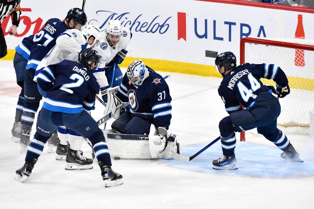 THE CANADIAN PRESS/Fred Greenslade
Winnipeg Jets goaltender Connor Hellebuyck (37) makes a save as Tampa Bay Lightning Nicholas Paul (20) and Brayden Point (21) look for the rebound with Dylan Demelo (2) and Josh Morrissey (44) defending during the first period.