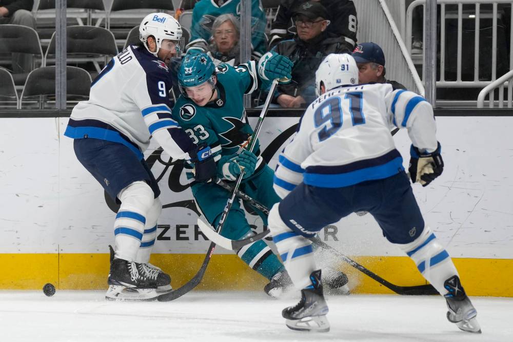San Jose Sharks defenceman Calen Addison battles along the boards with Winnipeg Jets left wing Alex Iafallo and centre Cole Perfetti during the second period. (AP Photo/Jeff Chiu)